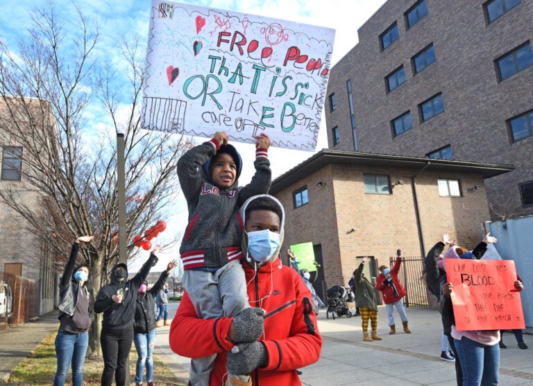 Leemaj Banks, 5, holds a sign while in the arms of his uncle Geovanni Andujar