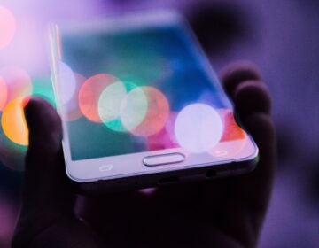 A person holds up a white cell phone.