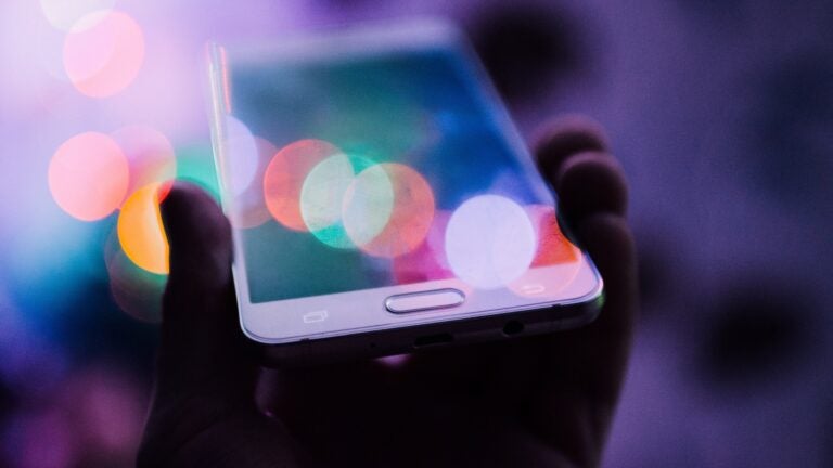 A person holds up a white cell phone.