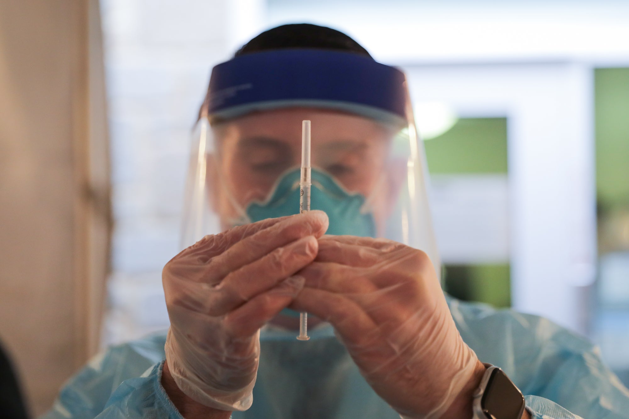 A health care worker holds up a syringe containing a COVID-19 vaccine at Roosevelt Care Center