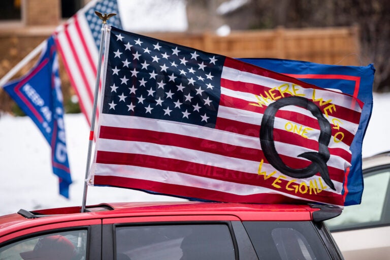 A car with a flag endorsing the QAnon conspiracy theory drives by as supporters of President Donald Trump gather for a rally outside the Governor's Residence on Nov. 14 in St. Paul, Minn