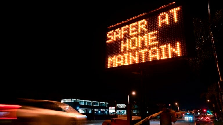 A sign reminds motorists of Los Angeles County's stay-at-home regulation. On Wednesday, the Centers for Disease Control and Prevention rolled out its revised guidelines for people potentially exposed to the coronavirus. (Frederic J. Brown/AFP via Getty Images)