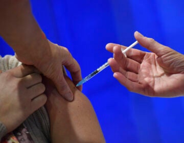 A woman receives an injection of the Pfizer-BioNTech Covid-19 vaccine at a health centre on the first day of the largest immunisation programme in the UK's history on December 8, 2020 in Cardiff, United Kingdom.