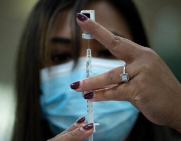 A pharmacist dilutes the Pfizer COVID-19 vaccine while preparing it to administer to staff and residents at the Goodwin House Bailey's Crossroads, a senior living community in Falls Church, Virginia, on December 30, 2020.