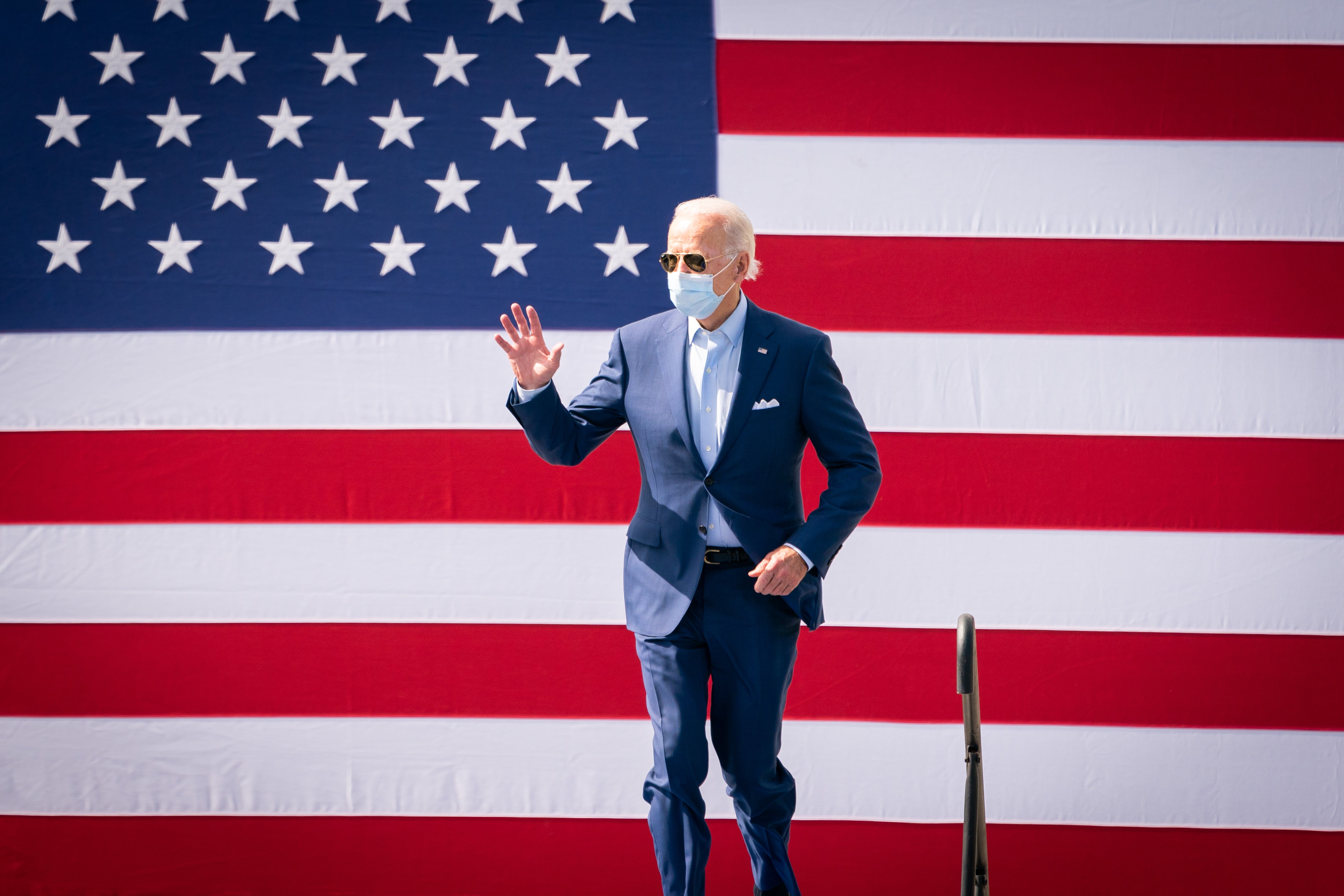 Joe Biden waves to a crowd of supporters at a campaign rally while wearing a mask