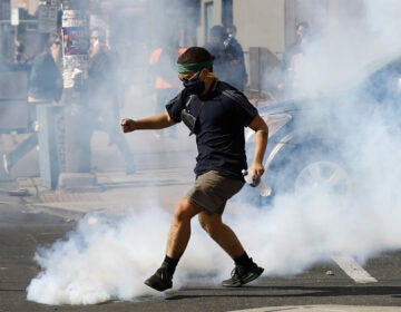 A protester kicks a tear gas canister fired by police as protests continue Sunday, May 31, 2020, in Philadelphia. (AP Photo/Matt Rourke)