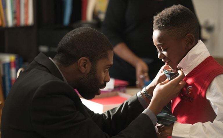 Director of music and operations Arreon Harley helps a young singer get ready for a Choir School of Delaware performance.