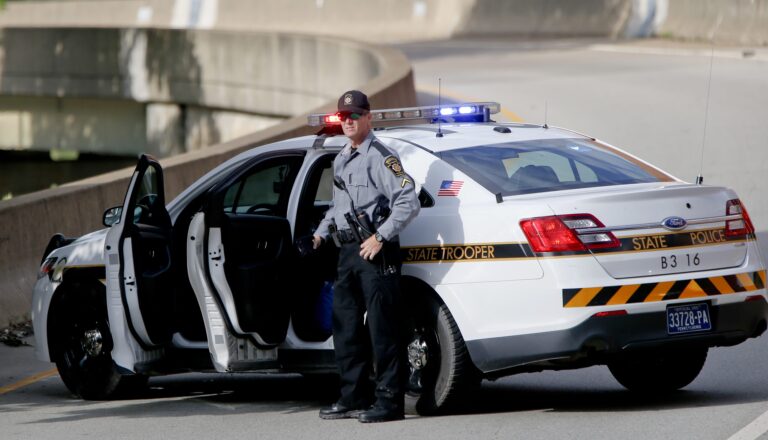 A Pennsylvania State Trooper stands beside his vehicle parked on the entrance ramp to Interstate 376 out of Pittsburgh as protesters block an intersection in downtown Pittsburgh, on Tuesday, June 26, 2018. (Keith Srakocic/AP Photo)