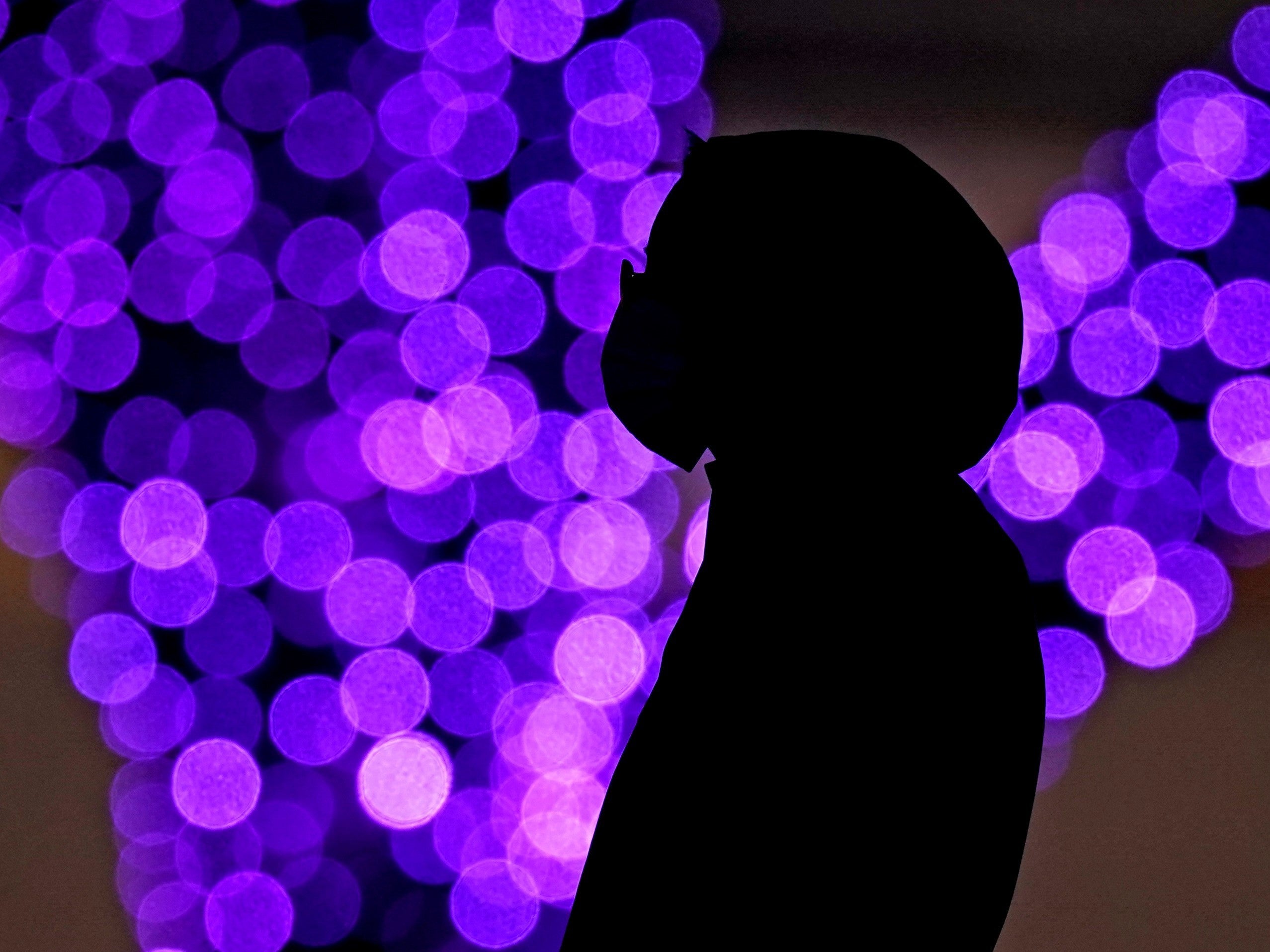 A woman wears masks to prevent the spread of the coronavirus as she looks at a holiday display