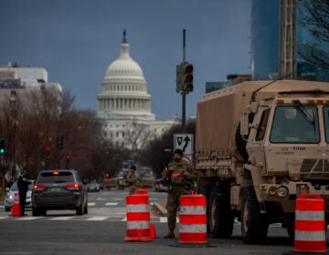 A military vehicle and orange traffic cones are pictured in front of the U.S. Capitol