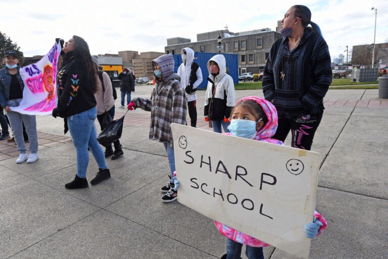 At a Jan. 6 protest at Camden's City Hall,  Ivonne Escobedo Rojas, 5, holds up a sign with the name of Sharp School. Sharp is among several public schools in the city that may be closed by the end of this month. (April Saul for WHYY)