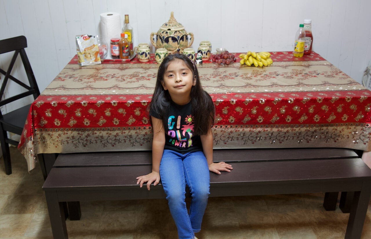 Krishna, 6, sits and smiles at the table where the families come together to eat dinner. | Krishna, de 6 años, se sienta y sonríe en la mesa donde las familias se reúnen para cenar. (Tony Rocco/WHYY)