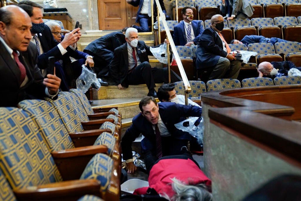 People shelter in the House gallery as pro-Trump insurrectionists try to break into the House Chamber at the U.S. Capitol