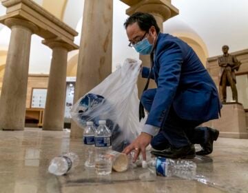 Rep. Andy Kim, D-N.J., cleans up debris and trash strewn across the floor in the early morning hours after protesters stormed the Capitol in Washington, Thursday, Jan. 7, 2021. (AP Photo/Andrew Harnik)