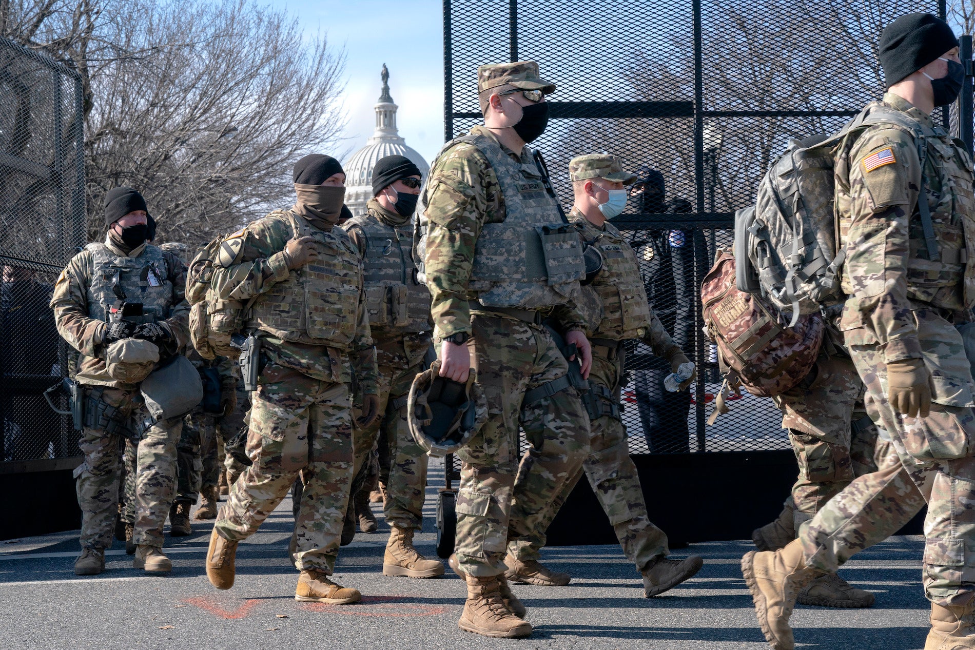 With the U.S. Capitol in the background, members of the National Guard change shifts as they exit through anti-scaling security fencing