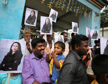 A child reacts as villagers hold placards featuring U.S. Vice President-elect Kamala Harris after participating in special prayers ahead of her inauguration, outside a Hindu temple in Thulasendrapuram, the hometown of Harris' maternal grandfather, south of Chennai, Tamil Nadu state, India, Wednesday, Jan. 20, 2021. A tiny, lush-green Indian village surrounded by rice paddy fields was beaming with joy Wednesday hours before its descendant, Kamala Harris, takes her oath of office and becomes the U.S. vice president. (AP Photo/Aijaz Rahi)