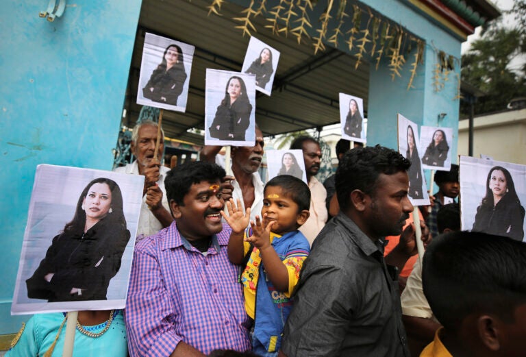 A child reacts as villagers hold placards featuring U.S. Vice President-elect Kamala Harris after participating in special prayers ahead of her inauguration, outside a Hindu temple in Thulasendrapuram, the hometown of Harris' maternal grandfather, south of Chennai, Tamil Nadu state, India, Wednesday, Jan. 20, 2021. A tiny, lush-green Indian village surrounded by rice paddy fields was beaming with joy Wednesday hours before its descendant, Kamala Harris, takes her oath of office and becomes the U.S. vice president. (AP Photo/Aijaz Rahi)
