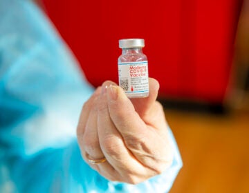 A woman holds a vial of the Moderna COVID-19 vaccine