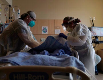 Registered nurses Robin Gooding, left, and Johanna Ortiz treat a COVID-19 patient