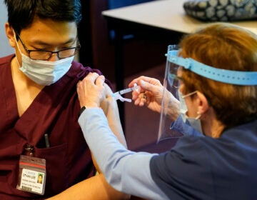 Pat Moore administers a covid-19 vaccine to Ethan Lee