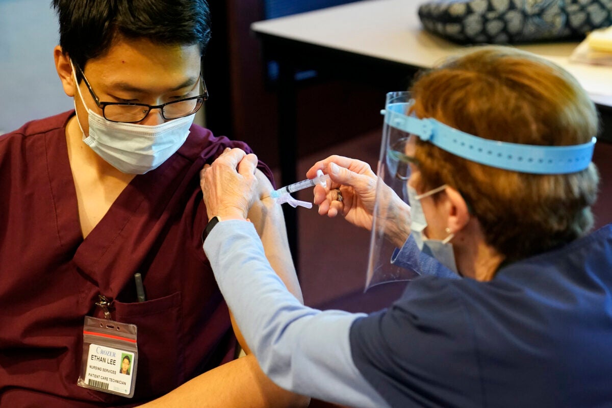 Pat Moore administers a covid-19 vaccine to Ethan Lee