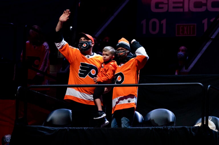 Josh and Amanda Hatheway, accompanied by their young son, wave from their seats at the Wells Fargo Center.