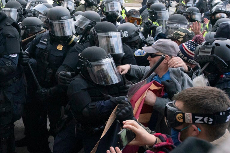 Capitol police officers in riot gear push back pro-Trump insurrectionists who try to break a door of the U.S. Capitol