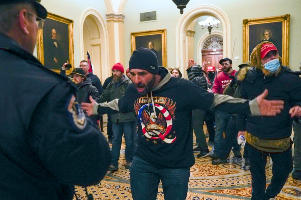 Pro-Trump insurrectionists gesture to U.S. Capitol Police in the hallway outside of the Senate chamber at the Capitol