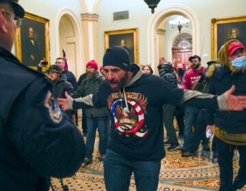 Pro-Trump insurrectionists gesture to U.S. Capitol Police in the hallway outside of the Senate chamber at the Capitol