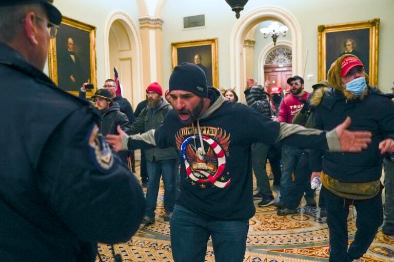 Pro-Trump insurrectionists gesture to U.S. Capitol Police in the hallway outside of the Senate chamber at the Capitol