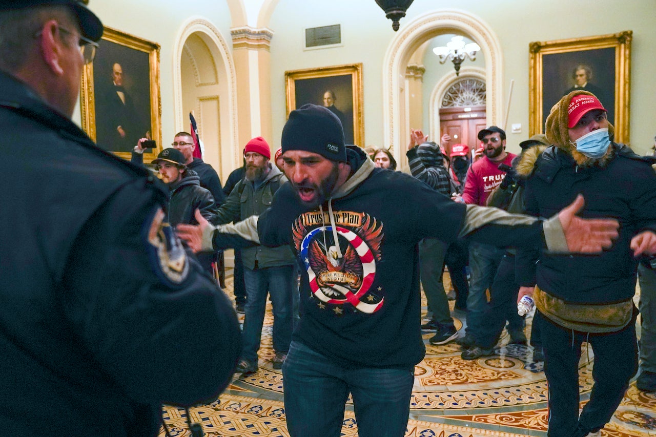 Pro-Trump insurrectionists gesture to U.S. Capitol Police in the hallway outside of the Senate chamber at the Capitol