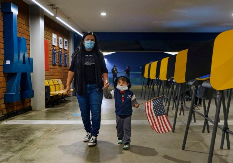 Lisa Carrera and her 2-year-old grandson Maverick hold hands as they walk inside a polling place