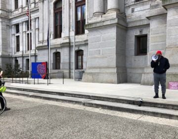 A passerby photographs activist Jamal Johnson who began his hunger strike Monday. (Layla Jones/WHYY)