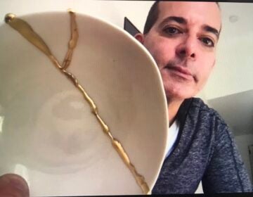 Dr. Matthew Beshara holds up a piece of pottery