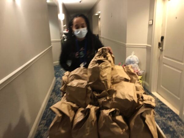 Cassie Brown pushes a cart filled with catered meals down a hallway. Each bag contains enough food for a day. (Cris Barrish/WHYY)
