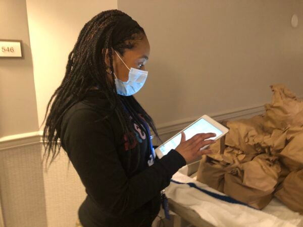 Cassie Brown documents meal deliveries and wellness checks on her tablet. (Cris Barrish/WHYY)