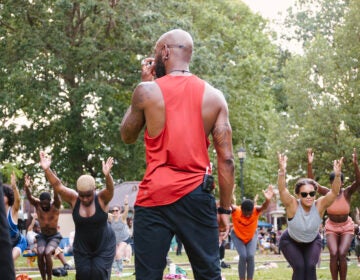 A Black yoga instructor from Spirits Up! leads an exercise class outside for people of color