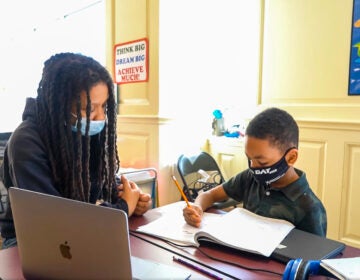 A young black girl and boy studying and doing homework with masks on