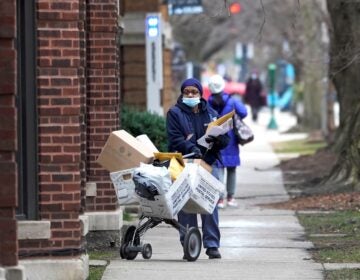 A U.S. postal worker delivers packages, boxes and letters on the sidewalk