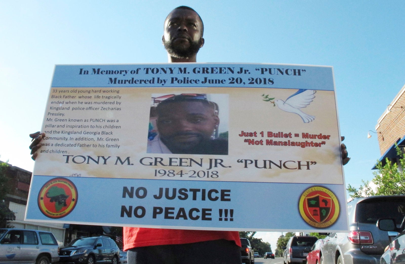 Tony White holds a sign showing a photograph of his slain cousin, Tony Green, outside Kingsland City Hall