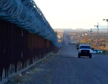 A U.S. Border Patrol vehicle drives along the border fence