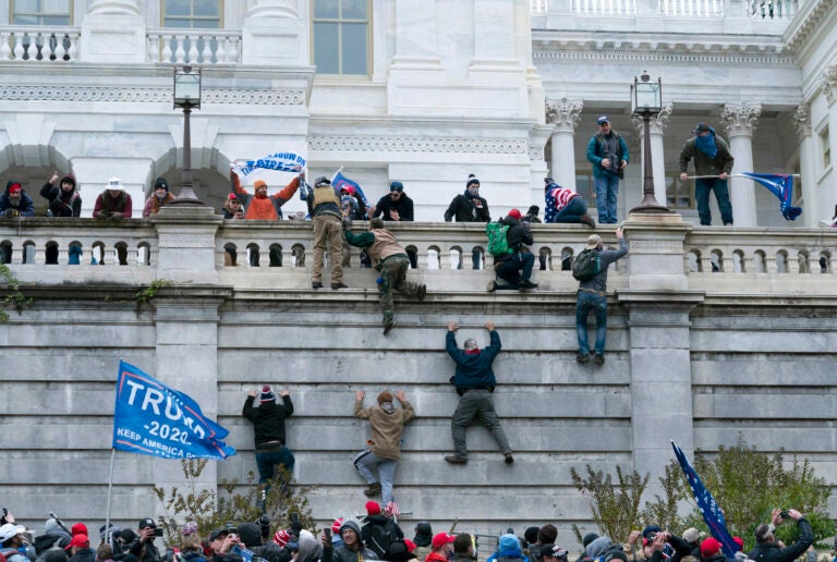 Pro-Trump insurrectionists climb the west wall of the the U.S. Capitol