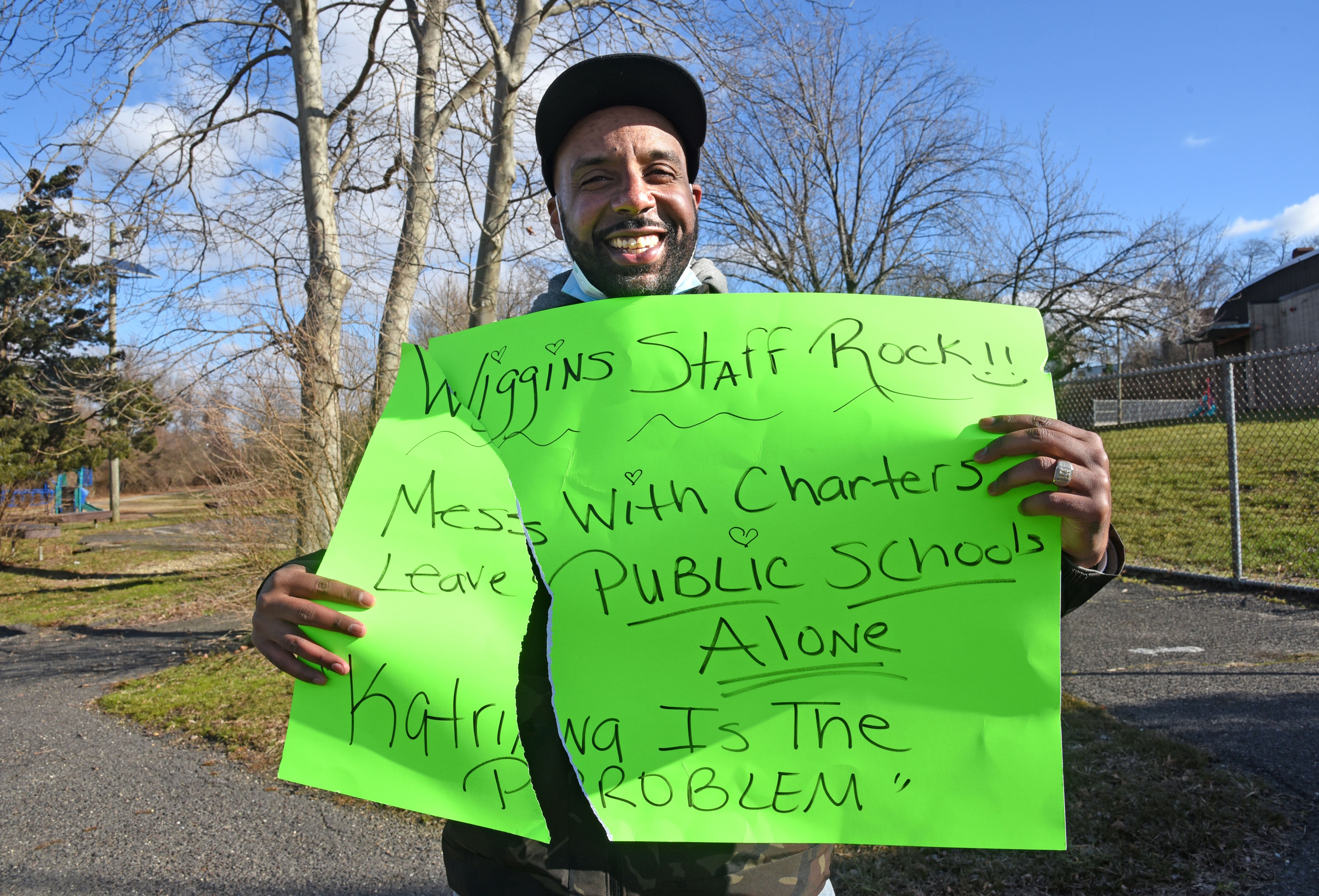 CEA president Keith Benson Jr. holds up a sign torn by the wind after he walked from Wiggins School