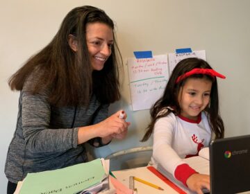 Chantelly Manzanares holds a marker while her daughter Rosabella attends class via Zoom