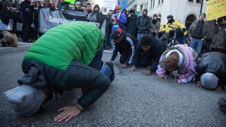 Abdulazeem Sheikh, 22, leads others from the group Young Muslims in afternoon prayer. Thousands of protesters gathered at Thomas Paine Plaza for a March for Humanity in support of refugees and immigrants in Philadelphia on Feb. 4, 2017.  (Emily Cohen for WHYY)