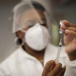 A health care worker holds a syringe containing the Moderna COVID-19 vaccine