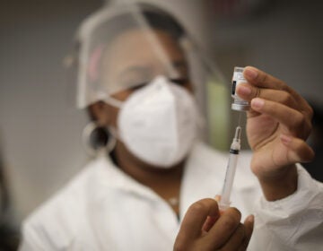 A health care worker holds a syringe containing the Moderna COVID-19 vaccine