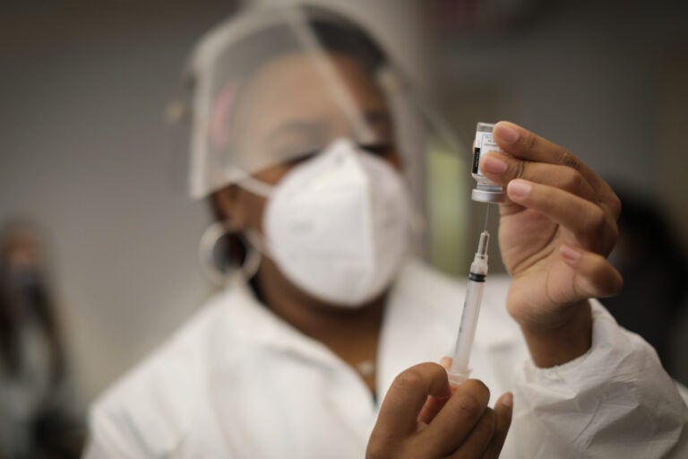 A health care worker holds a syringe containing the Moderna COVID-19 vaccine