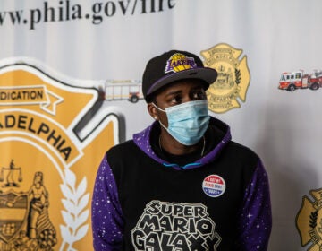 Eric Crawford sits in front of a Philadelphia Fire Department banner while wearing a mask