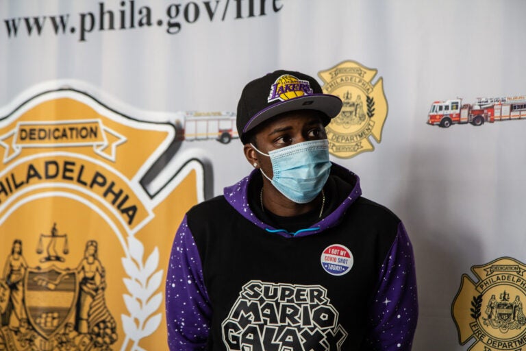 Eric Crawford sits in front of a Philadelphia Fire Department banner while wearing a mask